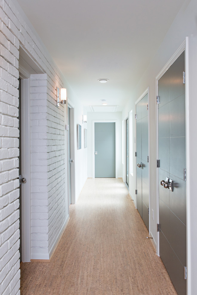 This is an example of a large midcentury hallway in Denver with white walls and cork floors.