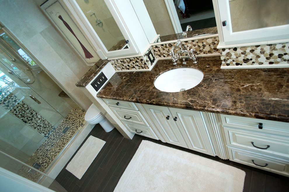 Photo of a mid-sized traditional master bathroom in Los Angeles with an undermount sink, raised-panel cabinets, beige cabinets, marble benchtops, a drop-in tub, an alcove shower, a one-piece toilet, brown tile, mosaic tile, beige walls and porcelain floors.