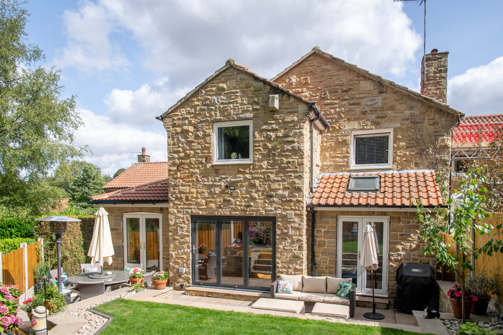 Inspiration for a brown traditional two floor detached house in Other with stone cladding, a pitched roof, a tiled roof and a red roof.