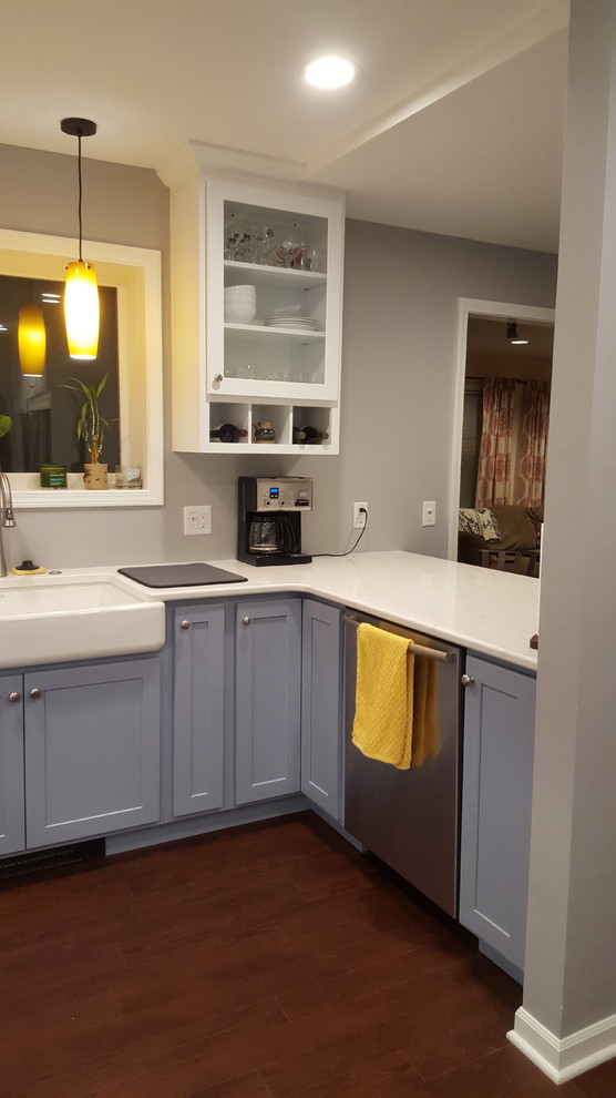 Example of a mid-sized transitional u-shaped vinyl floor enclosed kitchen design with a farmhouse sink, recessed-panel cabinets, blue cabinets, quartz countertops, stainless steel appliances and a peninsula