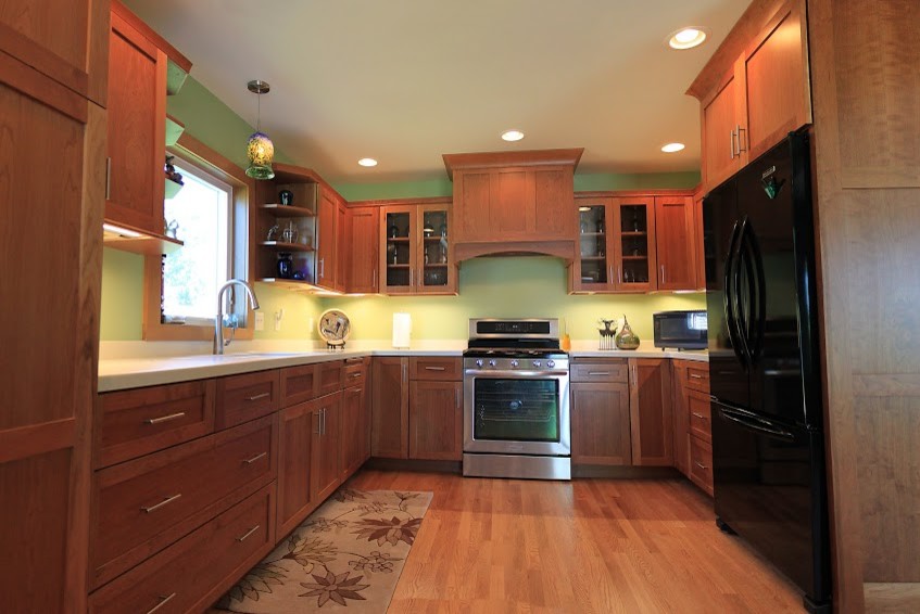 Inspiration for a mid-sized modern u-shaped light wood floor eat-in kitchen remodel with an undermount sink, flat-panel cabinets, medium tone wood cabinets, solid surface countertops and stainless steel appliances