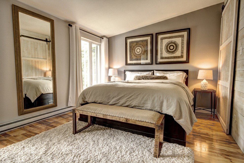Photo of a mid-sized country master bedroom in Montreal with grey walls and light hardwood floors.