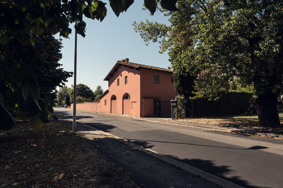 Photo of a large contemporary one-storey stucco pink apartment exterior in Florence with a gable roof, a tile roof and a red roof.