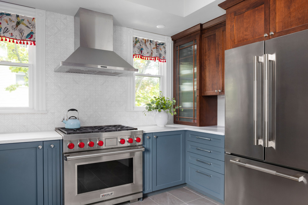 This is an example of a traditional u-shaped kitchen in Boston with a farmhouse sink, shaker cabinets, blue cabinets, quartz benchtops, grey splashback, mosaic tile splashback, stainless steel appliances, porcelain floors, a peninsula, grey floor, white benchtop and recessed.