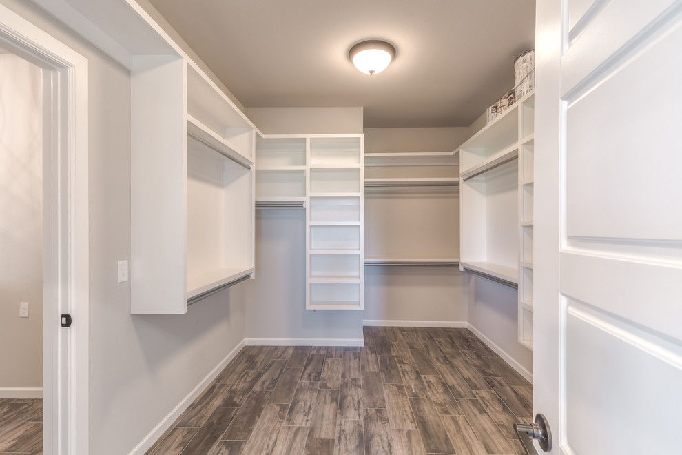 Design ideas for a large country gender-neutral walk-in wardrobe in Other with open cabinets, white cabinets, porcelain floors and brown floor.