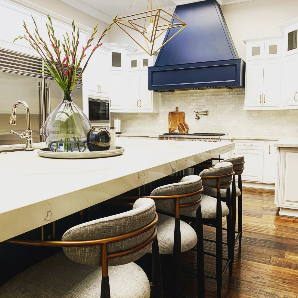 Huge transitional u-shaped medium tone wood floor, brown floor and vaulted ceiling eat-in kitchen photo in Phoenix with an undermount sink, recessed-panel cabinets, white cabinets, quartz countertops, white backsplash, ceramic backsplash, stainless steel appliances, an island and white countertops