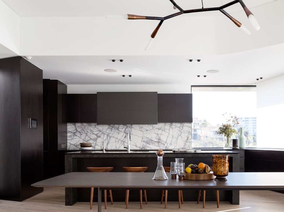 Photo of a modern galley eat-in kitchen in Sydney with with island, flat-panel cabinets, dark wood cabinets, light hardwood floors and marble splashback.