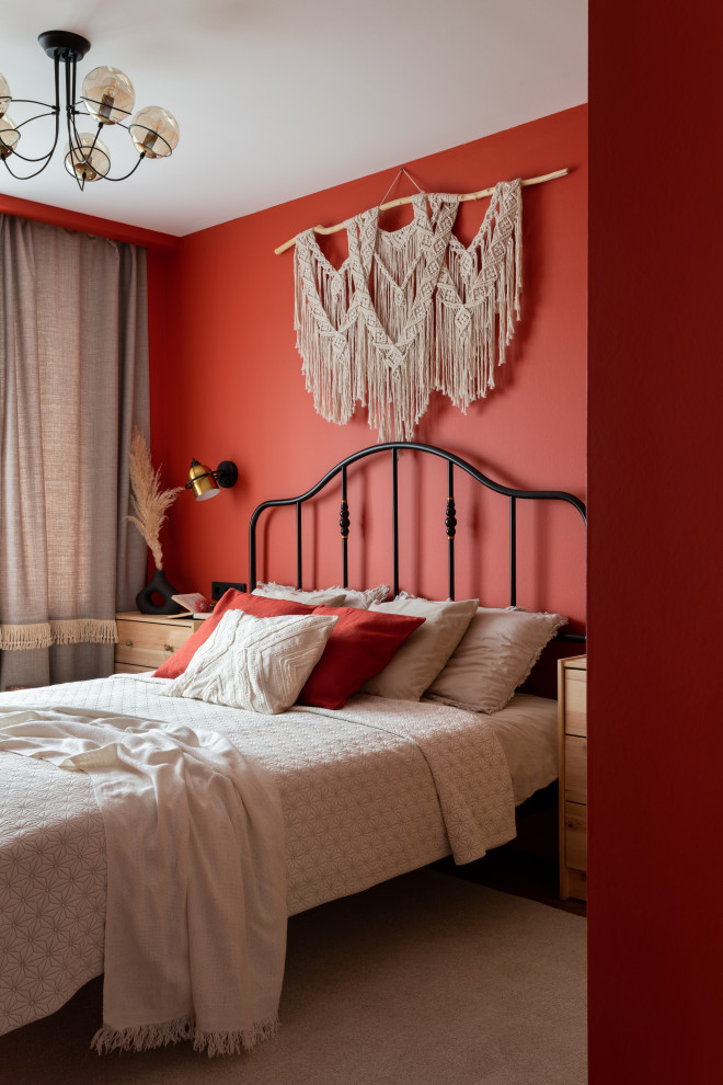 Cette image montre une petite chambre parentale avec un mur rouge et un sol en bois brun.