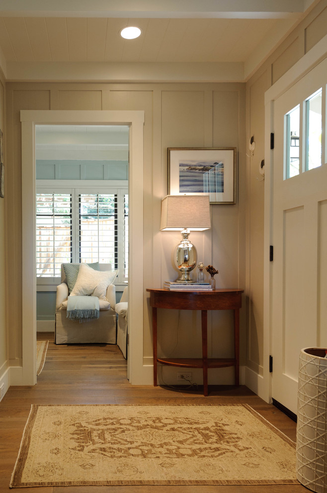 This is an example of a small beach style front door in Other with multi-coloured walls, medium hardwood floors, a single front door, a white front door and brown floor.