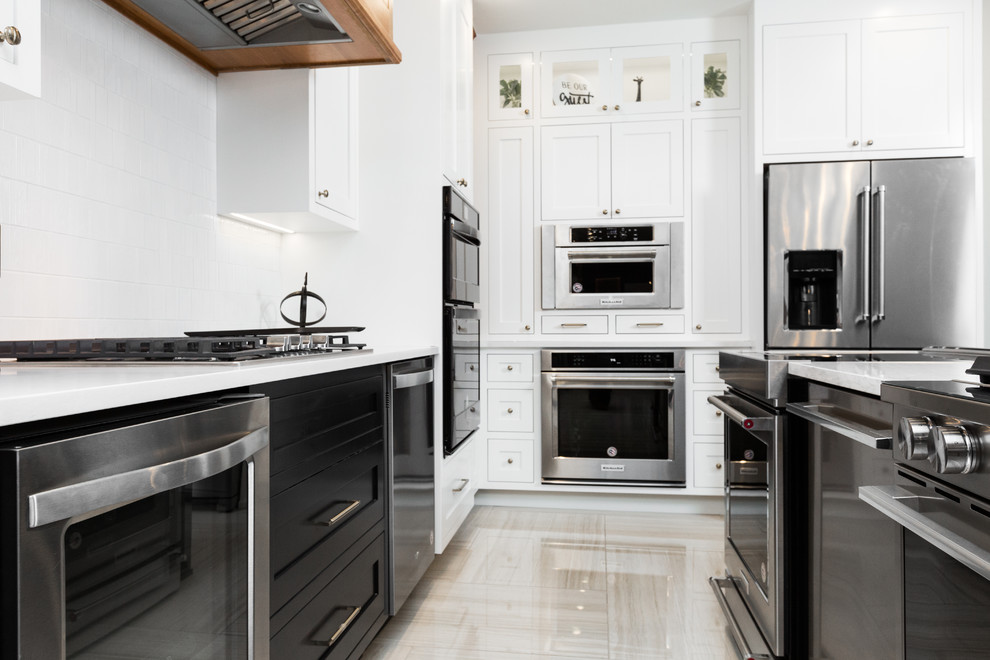 Enclosed kitchen - mid-sized transitional l-shaped porcelain tile and beige floor enclosed kitchen idea in Albuquerque with shaker cabinets, white cabinets, quartz countertops, white backsplash, mosaic tile backsplash, stainless steel appliances, an island and white countertops