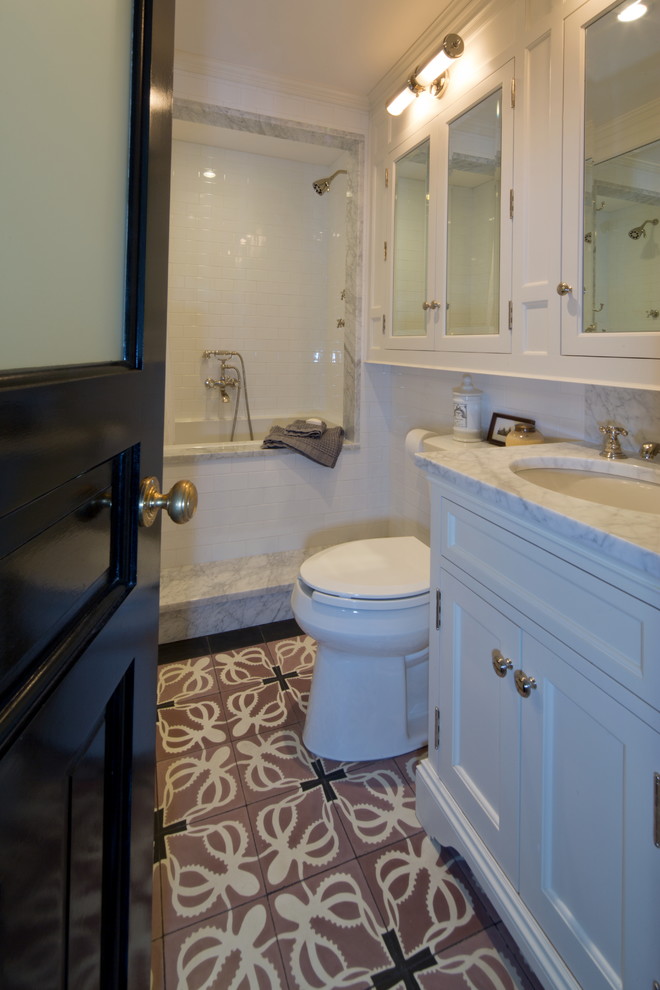 Small eclectic bathroom in New York with an undermount sink, flat-panel cabinets, white cabinets, marble benchtops, an undermount tub, a shower/bathtub combo, a two-piece toilet, white tile, ceramic tile, white walls and concrete floors.