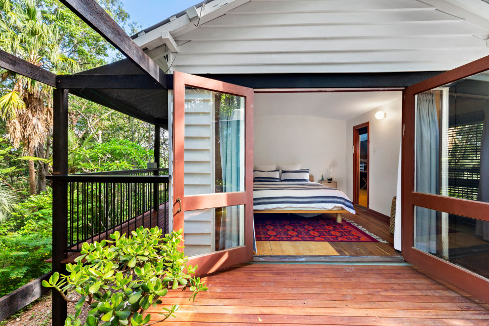 Inspiration for an expansive midcentury master bedroom in Brisbane with white walls, dark hardwood floors, brown floor, vaulted and wood walls.