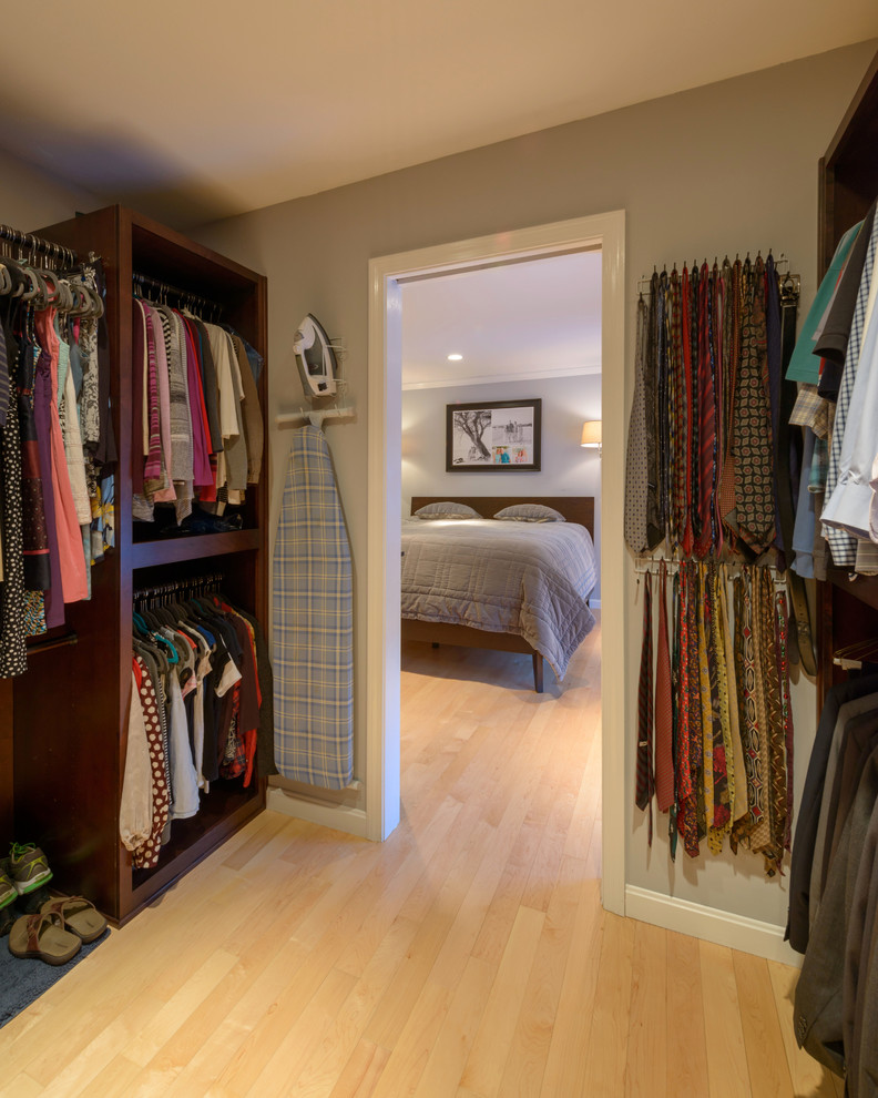 Transitional gender-neutral walk-in wardrobe in Boston with shaker cabinets, dark wood cabinets and light hardwood floors.