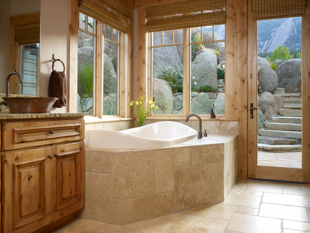 Photo of a large traditional master bathroom in Denver with raised-panel cabinets, medium wood cabinets, a drop-in tub, beige walls, travertine floors, a vessel sink and granite benchtops.