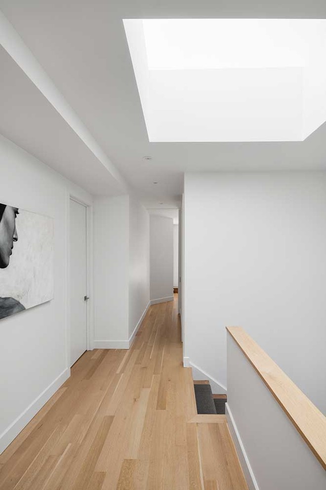 Mid-sized contemporary hallway in Montreal with white walls and medium hardwood floors.