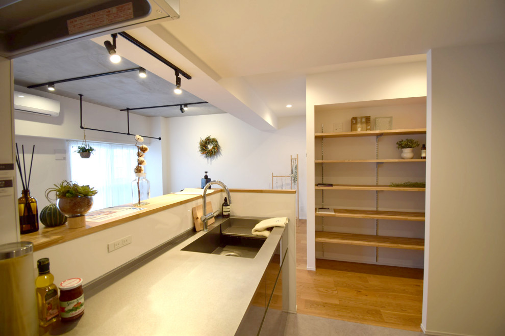 Идея дизайна: прямая кухня-гостиная в скандинавском стиле с фартуком цвета металлик, островом и коричневой столешницей
