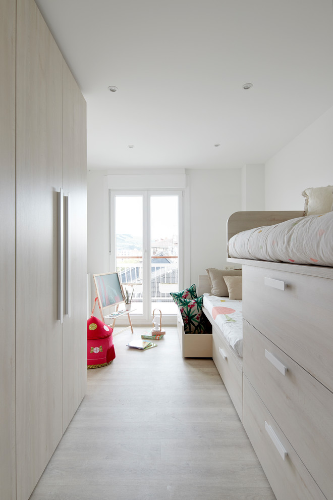 Photo of a mid-sized scandinavian gender-neutral kids' bedroom for kids 4-10 years old in Other with white walls, light hardwood floors and brown floor.