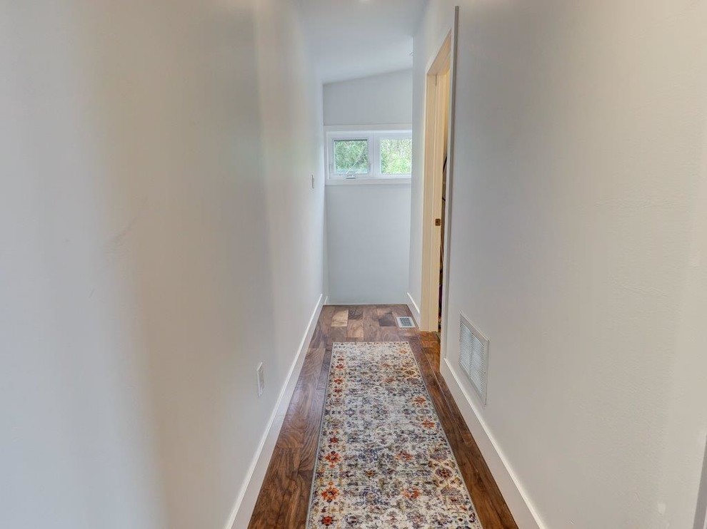This is an example of a mid-sized scandinavian hallway in Toronto with white walls, dark hardwood floors and brown floor.