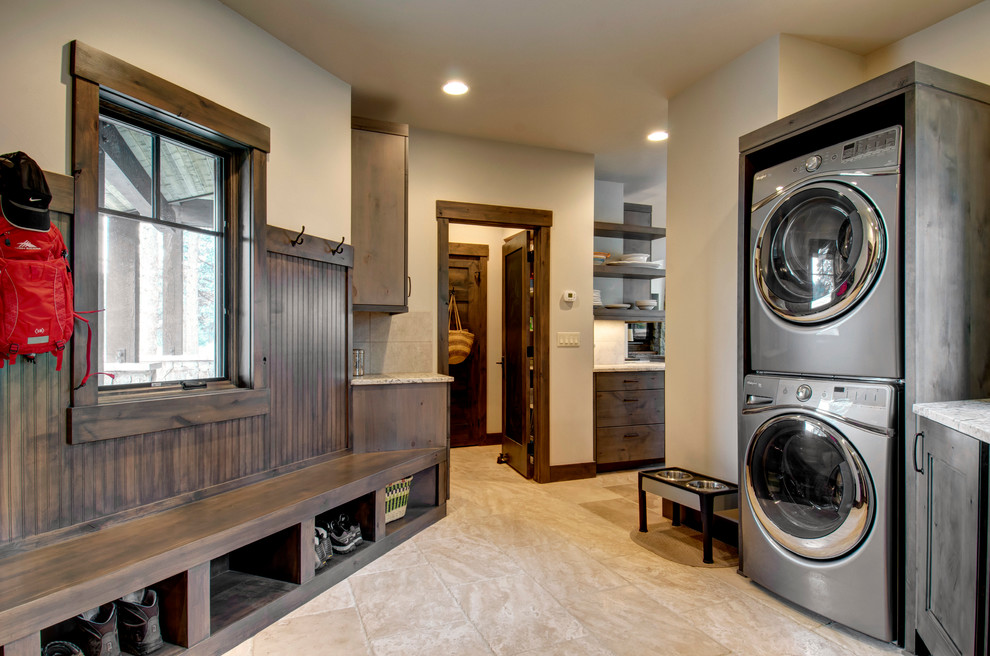 Inspiration for a country laundry room in Denver with recessed-panel cabinets, dark wood cabinets, beige walls, a stacked washer and dryer and beige floor.