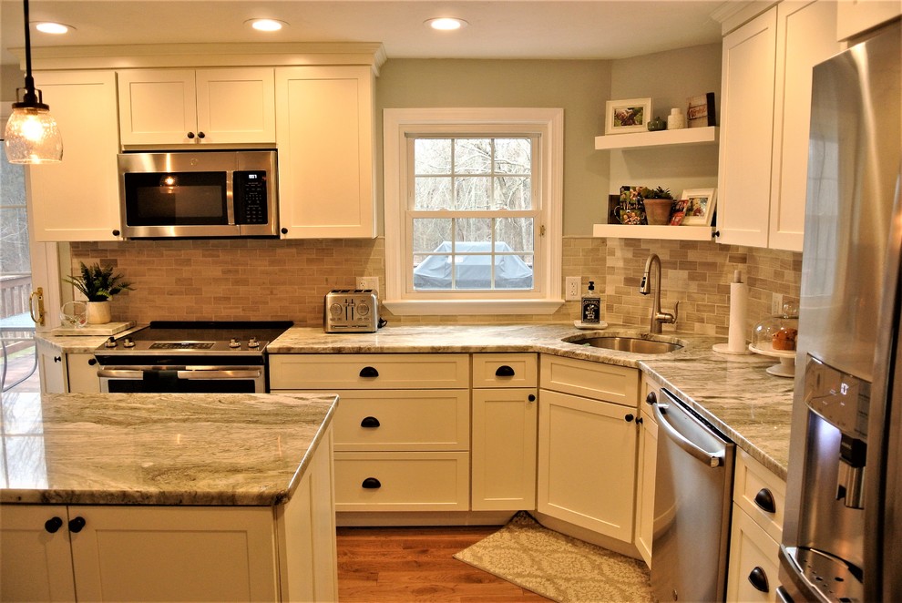 Inspiration for a transitional l-shaped medium tone wood floor kitchen remodel in Boston with an undermount sink, shaker cabinets, white cabinets, granite countertops, beige backsplash, subway tile backsplash, stainless steel appliances and an island