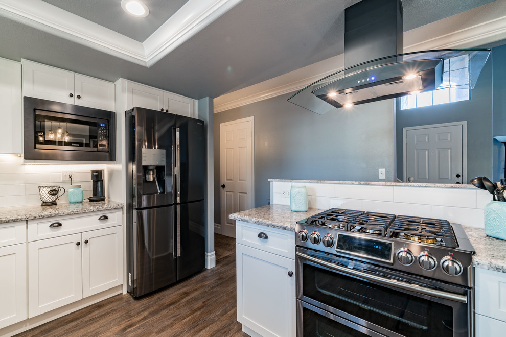 Mid-sized transitional u-shaped dark wood floor and brown floor eat-in kitchen photo with an undermount sink, shaker cabinets, white cabinets, granite countertops, white backsplash, subway tile backsplash, stainless steel appliances and an island