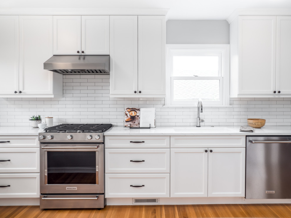 Small transitional galley separate kitchen in Seattle with an undermount sink, recessed-panel cabinets, quartzite benchtops, white splashback, porcelain splashback, stainless steel appliances, medium hardwood floors, brown floor and white benchtop.