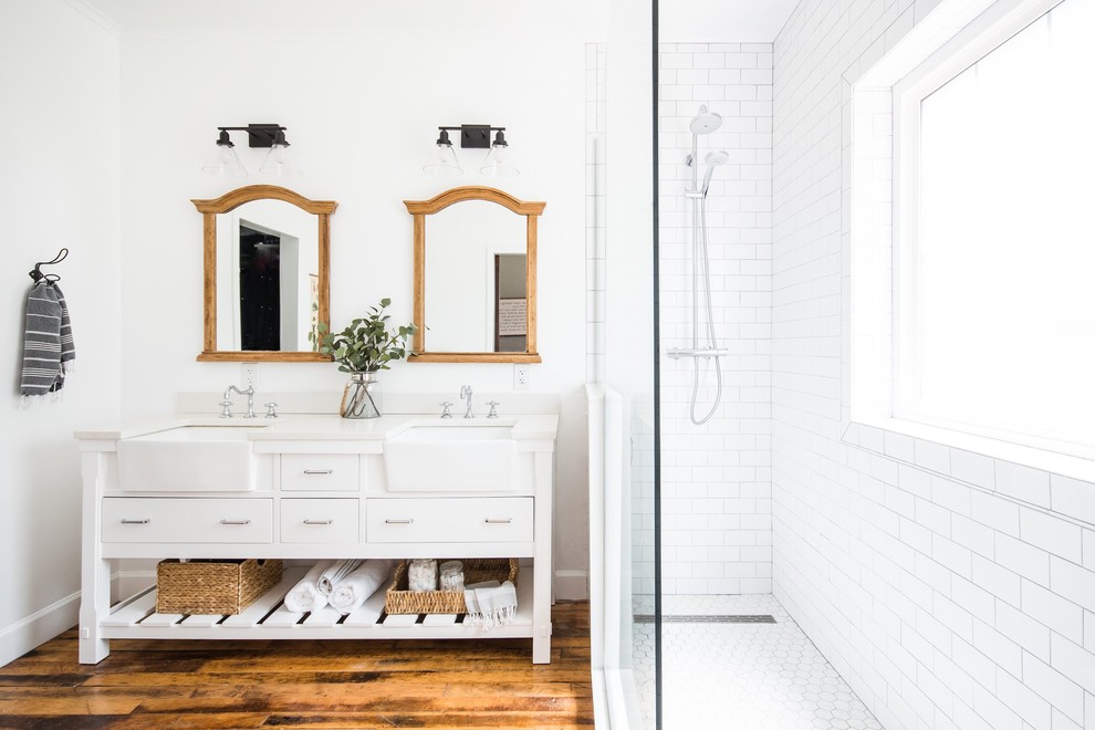 Photo of a country bathroom in Phoenix with flat-panel cabinets, white cabinets, a corner shower, white tile, subway tile, white walls, medium hardwood floors, an undermount sink, brown floor, an open shower and white benchtops.