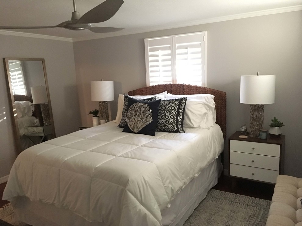 This is an example of a small beach style master bedroom in Tampa with grey walls, dark hardwood floors, no fireplace and brown floor.