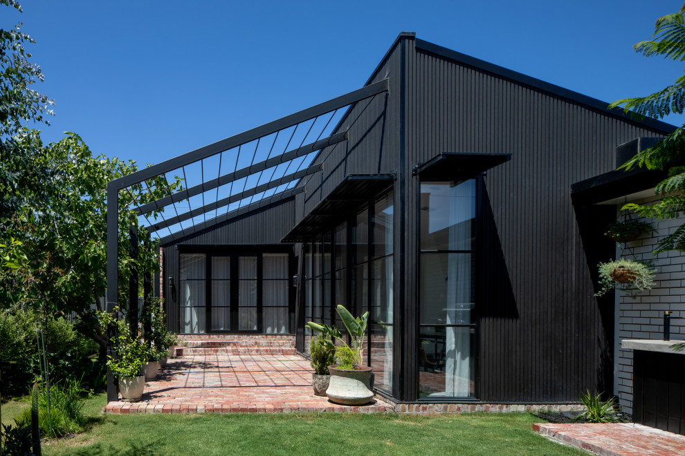 На фото: одноэтажный, деревянный, черный частный загородный дом среднего размера в современном стиле с крышей-бабочкой, металлической крышей и черной крышей