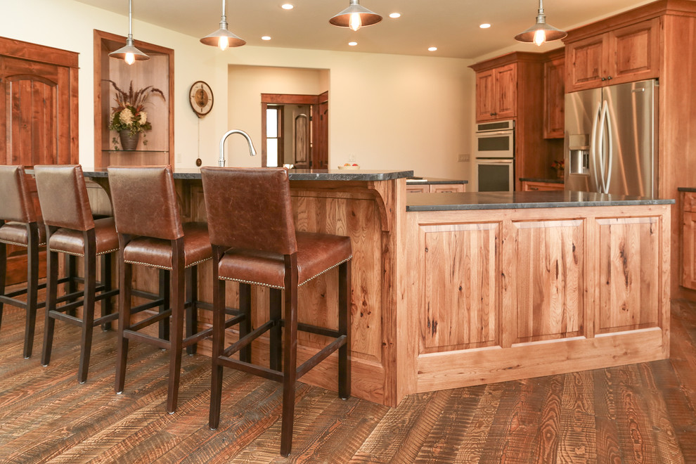 Example of a mid-sized mountain style l-shaped dark wood floor and brown floor open concept kitchen design with an undermount sink, raised-panel cabinets, medium tone wood cabinets, two islands and gray countertops