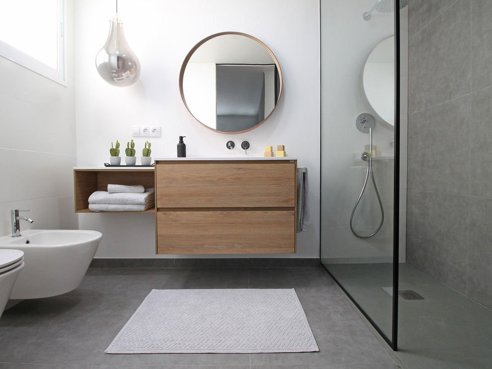 Mid-sized modern master bathroom in Valencia with flat-panel cabinets, medium wood cabinets, an open shower, a wall-mount toilet, gray tile, white walls, an integrated sink, grey floor and white benchtops.