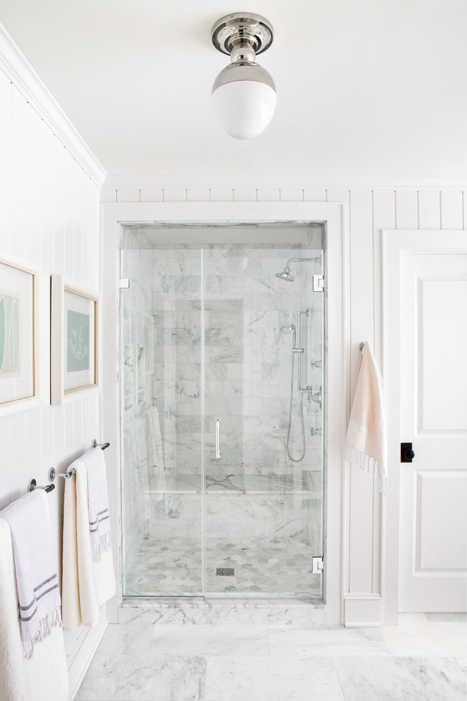 Mid-sized beach style master bathroom in New York with white cabinets, a freestanding tub, a corner shower, a one-piece toilet, gray tile, white tile, marble, white walls, marble floors, an undermount sink, marble benchtops, white floor, a hinged shower door and white benchtops.