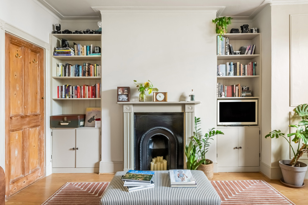 Mittelgroßes Klassisches Wohnzimmer mit beiger Wandfarbe, braunem Holzboden, Kaminumrandung aus Holz, freistehendem TV, braunem Boden und Wandpaneelen in London