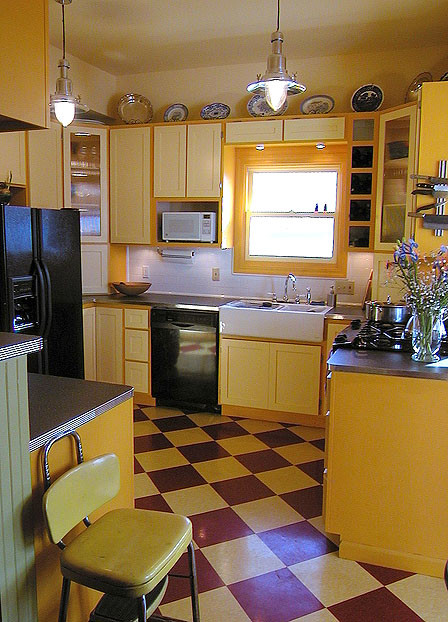 This is an example of a small country l-shaped separate kitchen in San Francisco with a farmhouse sink, shaker cabinets, yellow cabinets, laminate benchtops, white splashback, subway tile splashback, black appliances, linoleum floors and a peninsula.