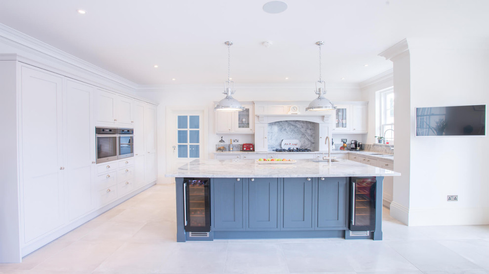 Photo of a large grey and black u-shaped open plan kitchen in Sussex with a single-bowl sink, shaker cabinets, grey cabinets, quartz worktops, grey splashback, stone slab splashback, integrated appliances, porcelain flooring, an island, grey floors, grey worktops and feature lighting.