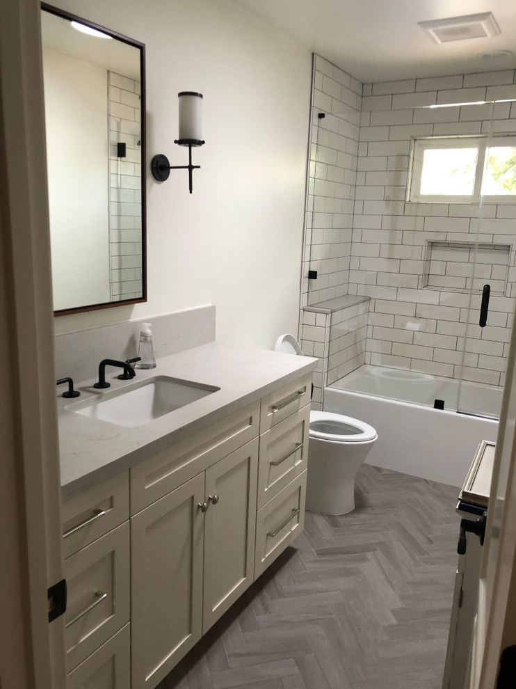 Inspiration for a small traditional 3/4 bathroom in San Francisco with recessed-panel cabinets, white cabinets, a drop-in tub, a shower/bathtub combo, a one-piece toilet, subway tile, beige walls, medium hardwood floors, an undermount sink, engineered quartz benchtops, beige floor, a sliding shower screen, grey benchtops, a single vanity and a freestanding vanity.