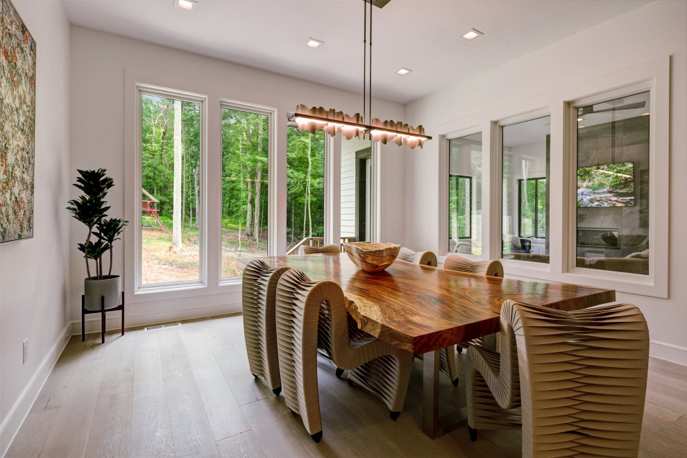 Immagine di una grande sala da pranzo aperta verso la cucina contemporanea con pareti bianche, parquet chiaro e pavimento grigio