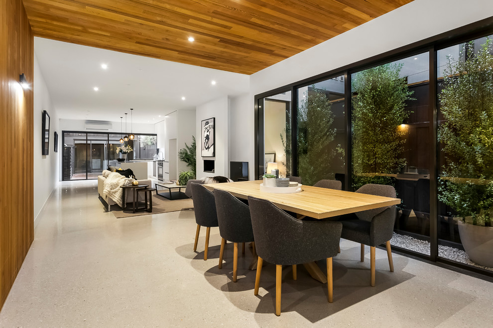 This is an example of a contemporary open plan dining in Melbourne with white walls and grey floor.