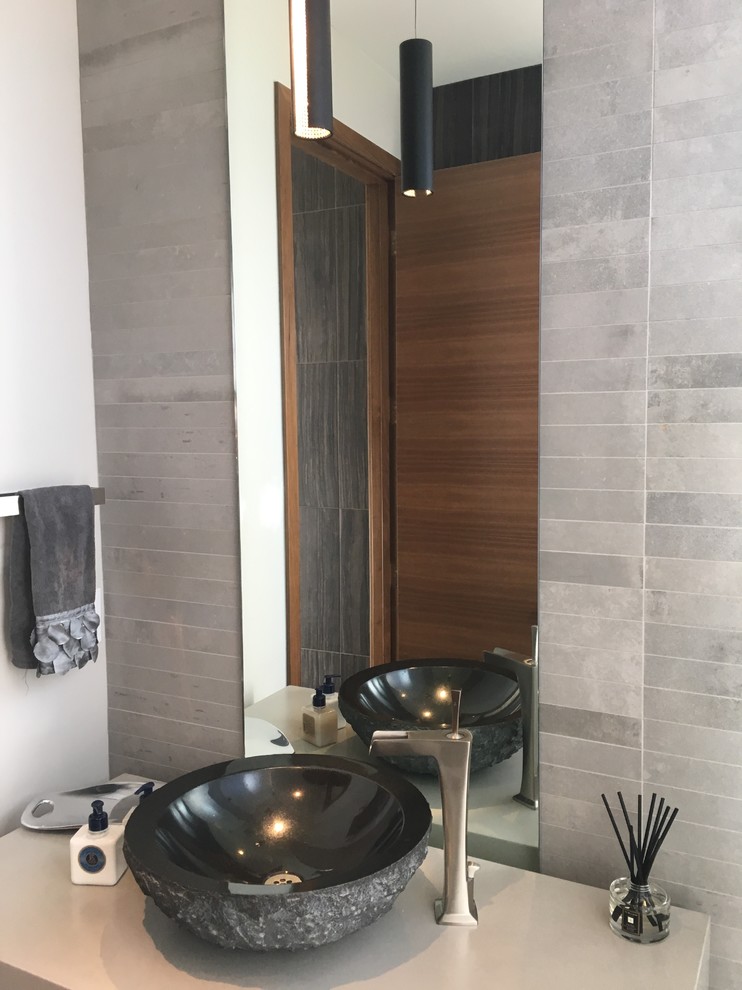 Inspiration for a mid-sized modern powder room in San Francisco with a one-piece toilet, gray tile, porcelain tile, black walls, porcelain floors, a vessel sink, concrete benchtops, grey floor and grey benchtops.