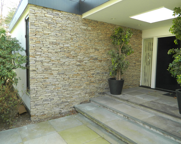 Example of a mid-sized minimalist front yard and one-story stone and mixed siding partial sun and white entryway design with a shingle roof