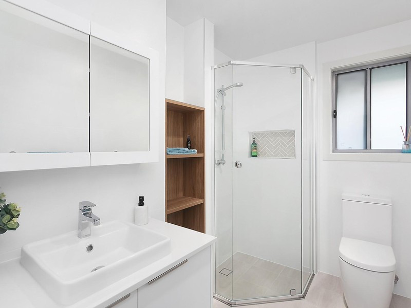 Inspiration for a small contemporary 3/4 bathroom in Other with white cabinets, a corner shower, a one-piece toilet, white tile, white walls, a drop-in sink, engineered quartz benchtops, a hinged shower door and white benchtops.