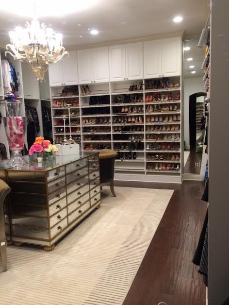 Expansive traditional women's walk-in wardrobe in New Orleans with recessed-panel cabinets, white cabinets and dark hardwood floors.