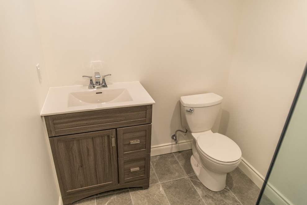 Photo of a small transitional 3/4 bathroom in Toronto with recessed-panel cabinets, dark wood cabinets, a corner shower, a two-piece toilet, white walls, slate floors, grey floor, white tile, ceramic tile, an integrated sink, engineered quartz benchtops, a hinged shower door and white benchtops.