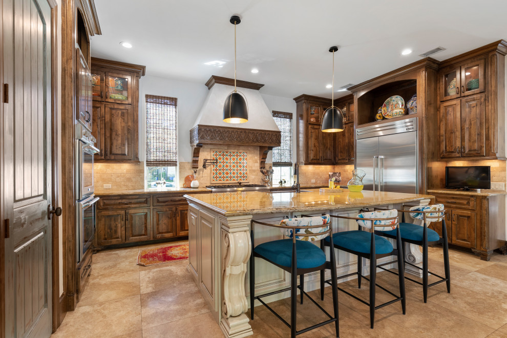 Design ideas for a mid-sized u-shaped eat-in kitchen in Houston with a farmhouse sink, raised-panel cabinets, brown cabinets, granite benchtops, beige splashback, travertine splashback, stainless steel appliances, travertine floors, with island, beige floor and orange benchtop.