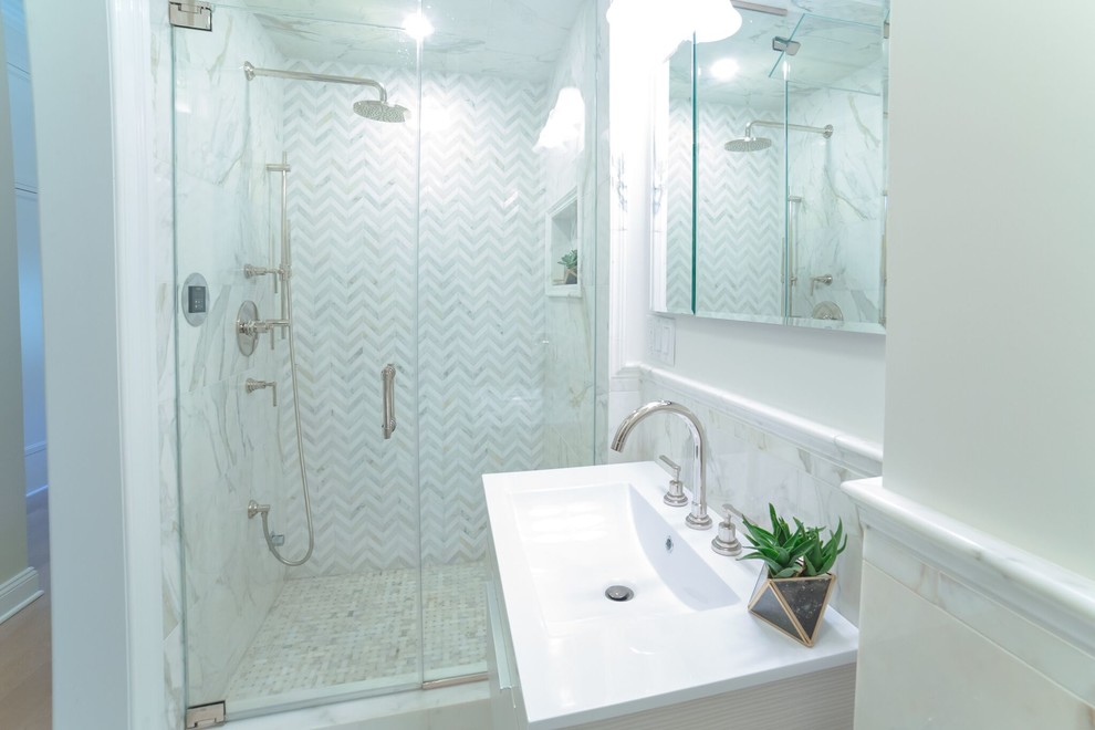 This is an example of a small contemporary master bathroom in New York with flat-panel cabinets, white cabinets, an undermount tub, an alcove shower, a wall-mount toilet, white tile, marble, blue walls, marble floors, an undermount sink, marble benchtops, white floor, an open shower and white benchtops.