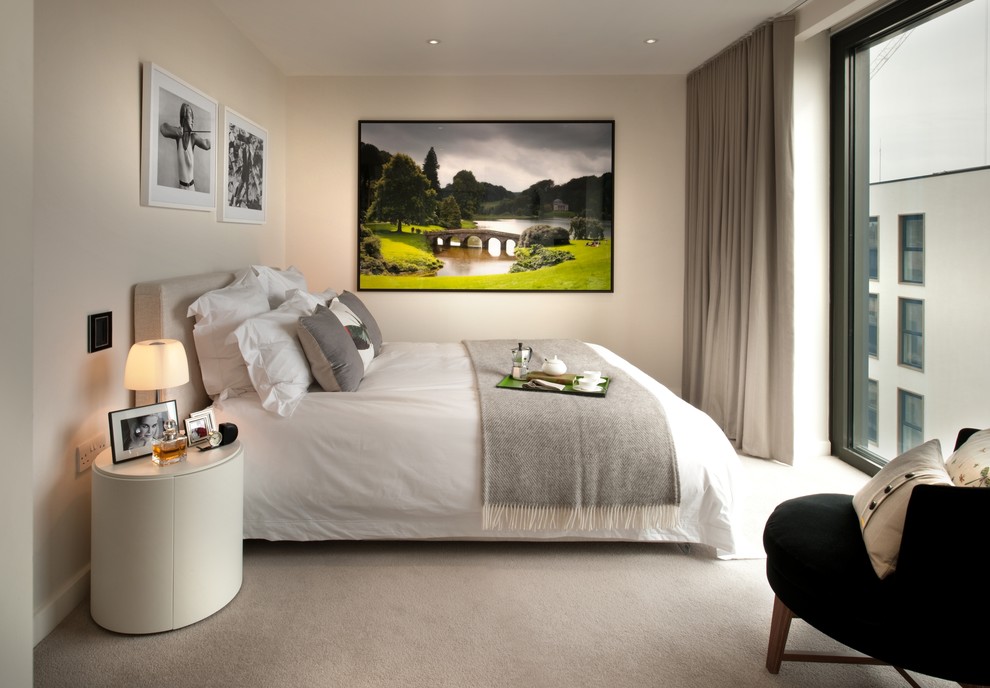 Mid-sized contemporary master bedroom in London with beige walls, carpet and beige floor.