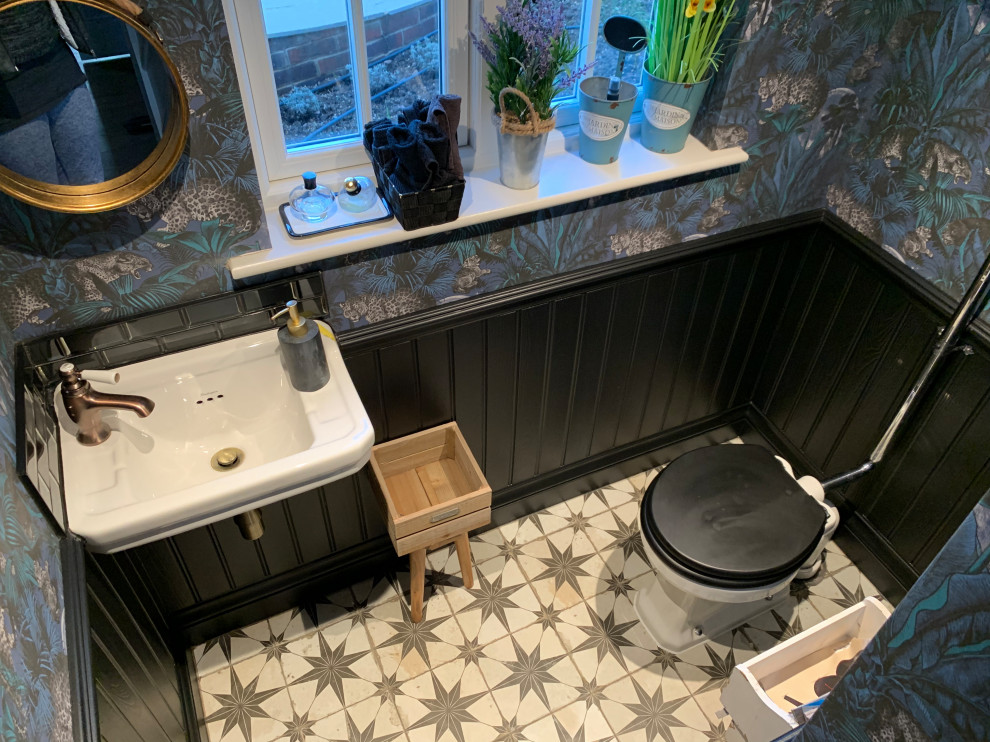 Стильный дизайн: маленький туалет в стиле фьюжн с раздельным унитазом, черной плиткой, стеклянной плиткой, синими стенами, полом из керамогранита, подвесной раковиной, разноцветным полом, балками на потолке и обоями на стенах для на участке и в саду - последний тренд