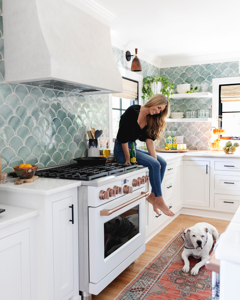 Inredning av ett modernt mellanstort vit vitt kök och matrum, med grönt stänkskydd, stänkskydd i glaskakel, plywoodgolv, en köksö och beiget golv