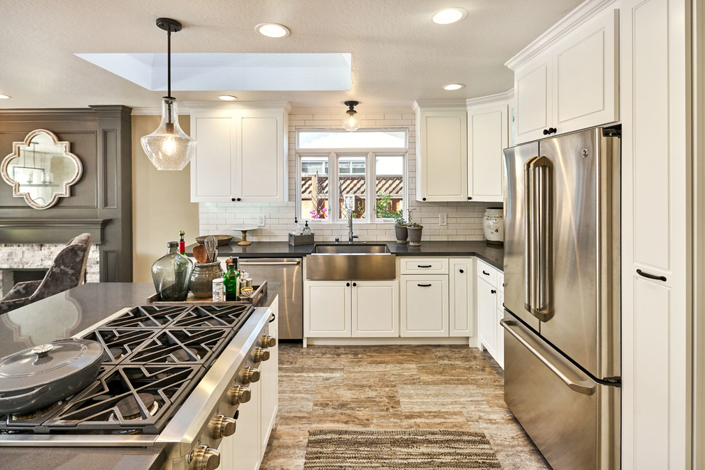 Large mountain style u-shaped porcelain tile and gray floor open concept kitchen photo in San Francisco with a farmhouse sink, raised-panel cabinets, white cabinets, soapstone countertops, white backsplash, subway tile backsplash, stainless steel appliances and an island