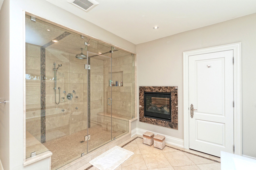 This is an example of a large transitional master bathroom in Toronto with raised-panel cabinets, white cabinets, a freestanding tub, an alcove shower, beige tile, grey walls, an undermount sink, limestone floors, beige floor and a hinged shower door.